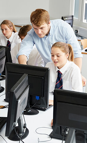 Students working in a computer room with a teacher